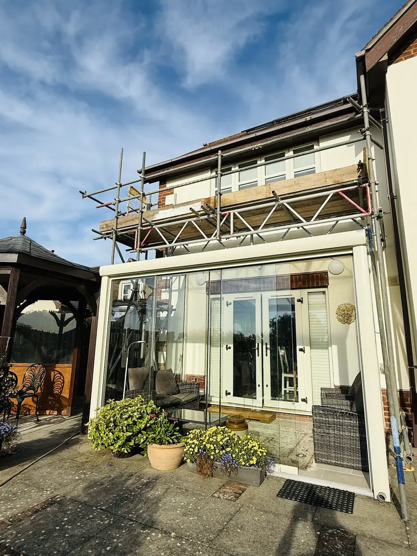 Bridging scaffold over a glass garden room