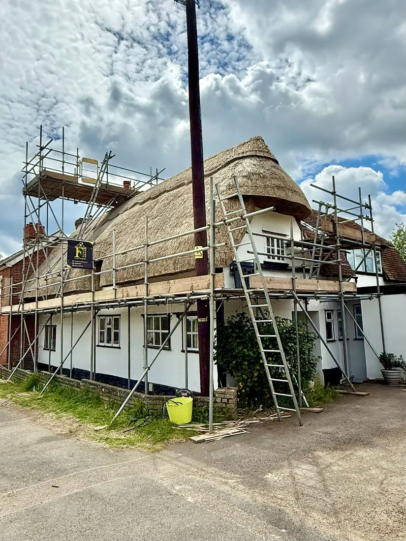 Scaffolding around a thatched cottage